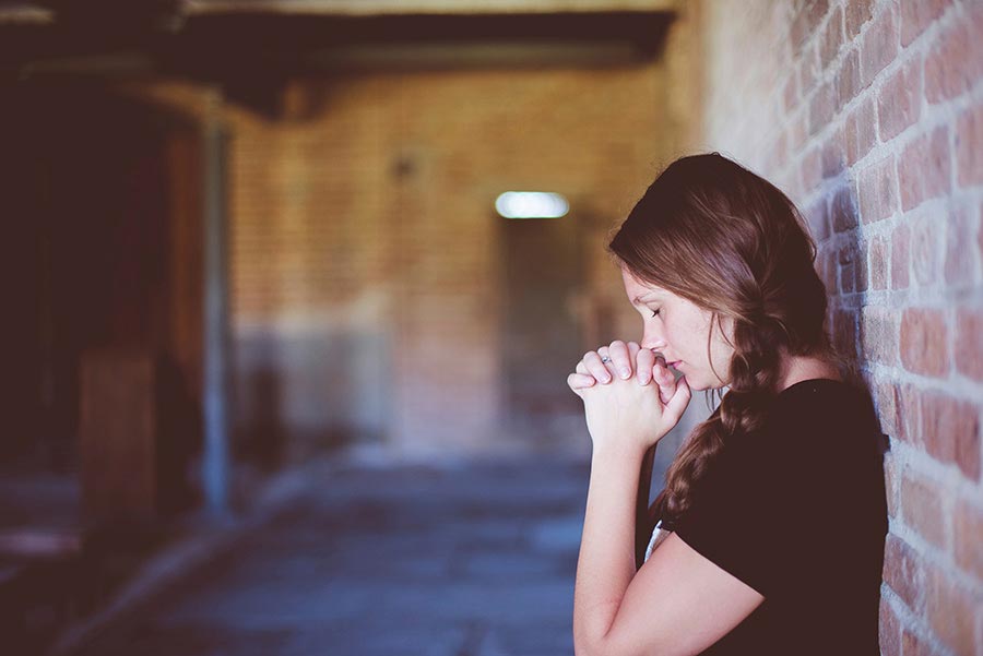 A woman praying to God, expressing her faith and coping with chronic illness